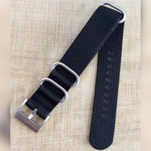 Kundens bilde: svart NATO strap med sølvfarget spenne og tre ringer på et trebord