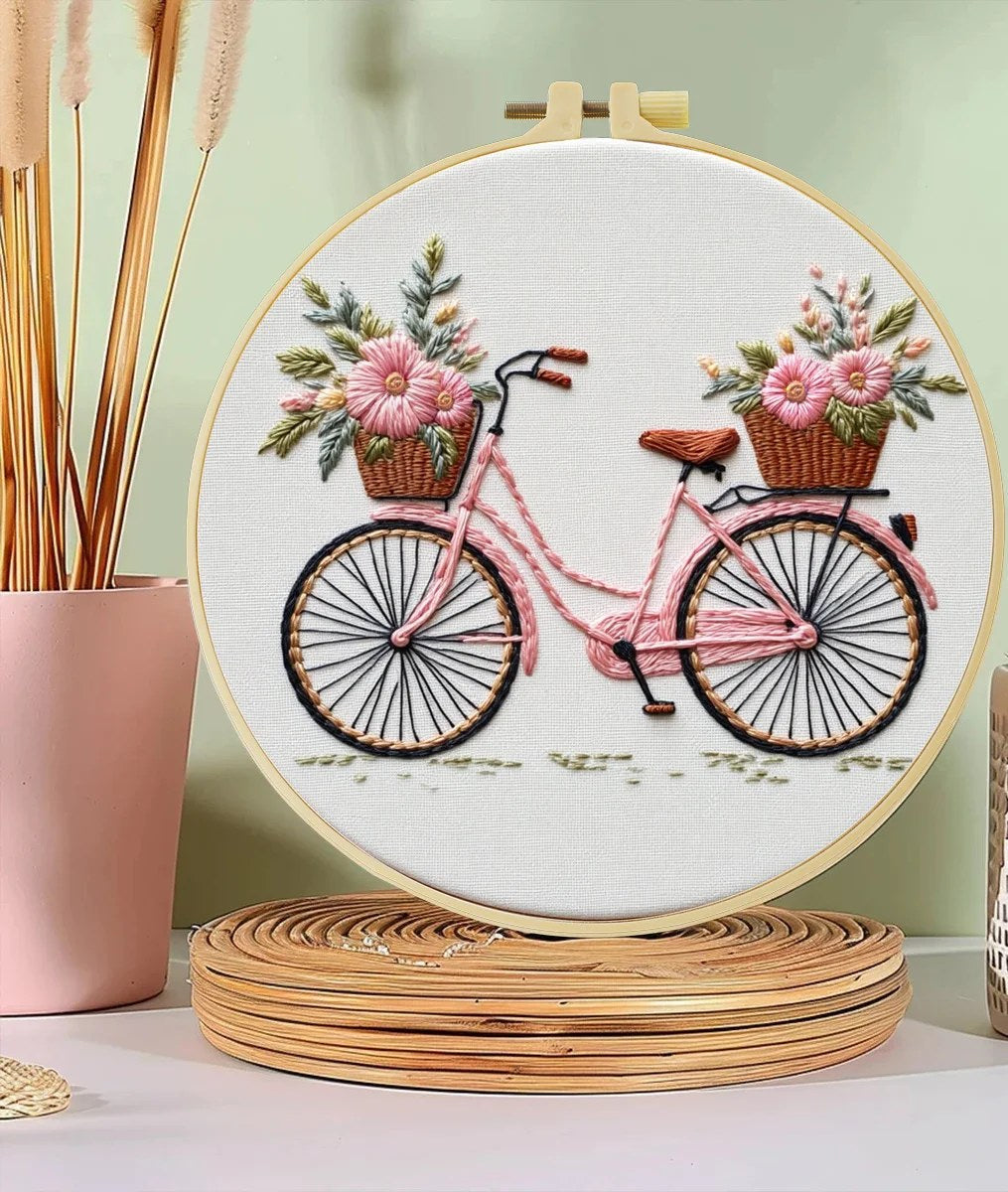Broderisett med sykkel og blomsterkurver i broderirammen