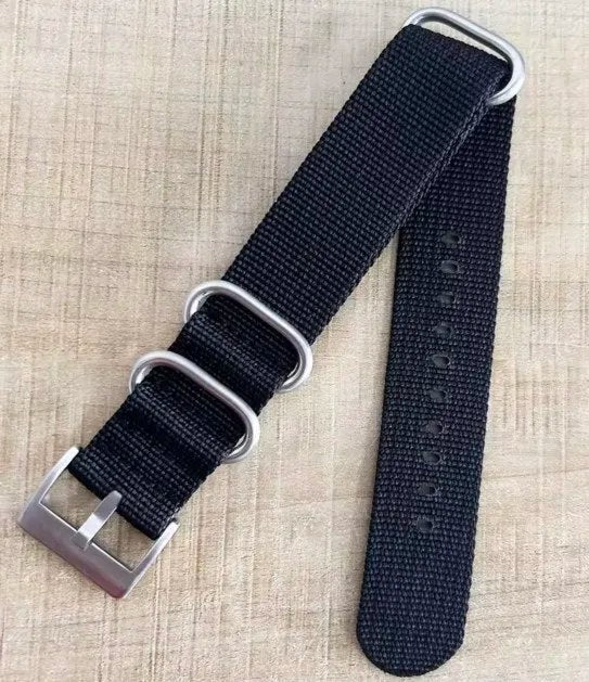 Svart NATO strap med sølvfarget spenne og tre ringer