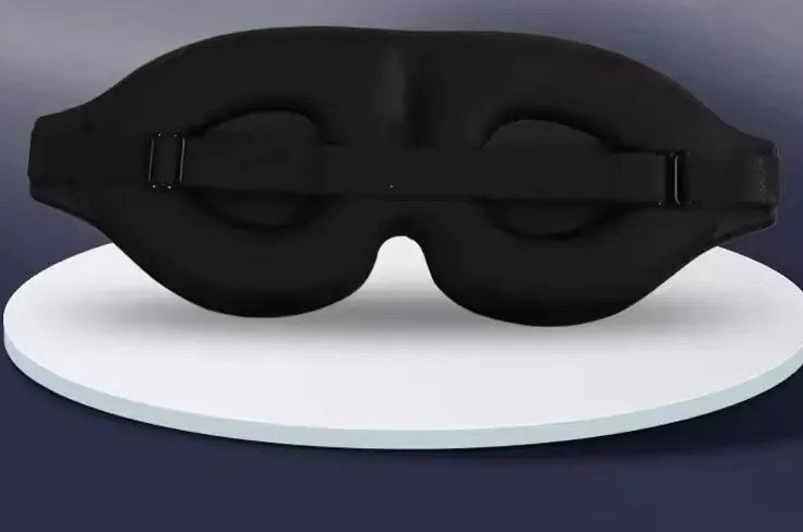 Svart 3D-sovemaske sett bakfra: fordypninger til øynene og stropp med spenne