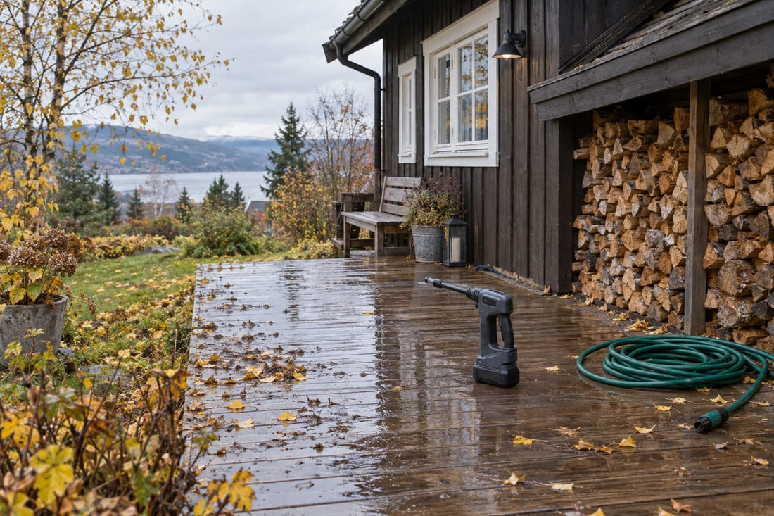 Norsk hus om høsten sett fra hagen, med våt terrasse, hageslange, høytrykkspyler og vedstabel under takutstikket