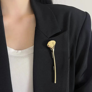 Gullfarget brosje formet som et ginkgoblad, loddrett på en svart blazer