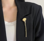 Gullfarget brosje formet som et ginkgoblad, loddrett på en svart blazer