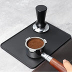 Tampermatten sett ovenfra med en tamper og en portafilter med kaffe