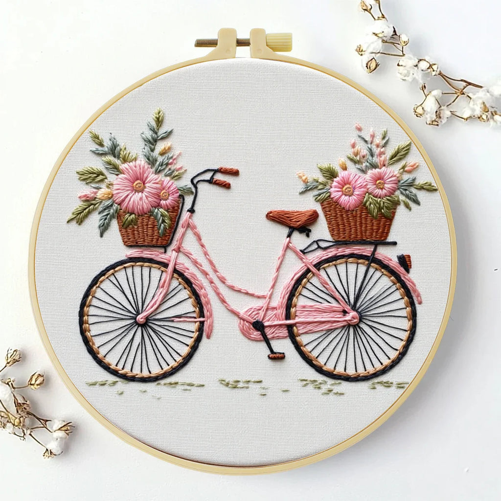 Det ferdige broderiet med rosa sykkel og blomsterkurver i rammen på Ø 20 cm