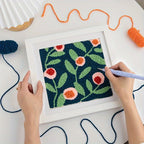 Bilde med blomster laget med punch needle i en hvit ramme