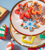 Pepperkakeformer formet som snøkrystall og pepperkakemann på et kakefat med pyntede pepperkaker