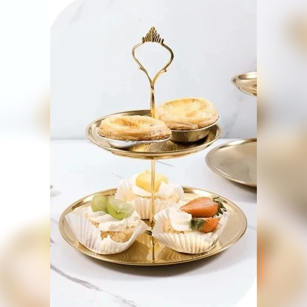 Etasjefatet i 2 etasjer med små terter og kremkaker på et lyst bord