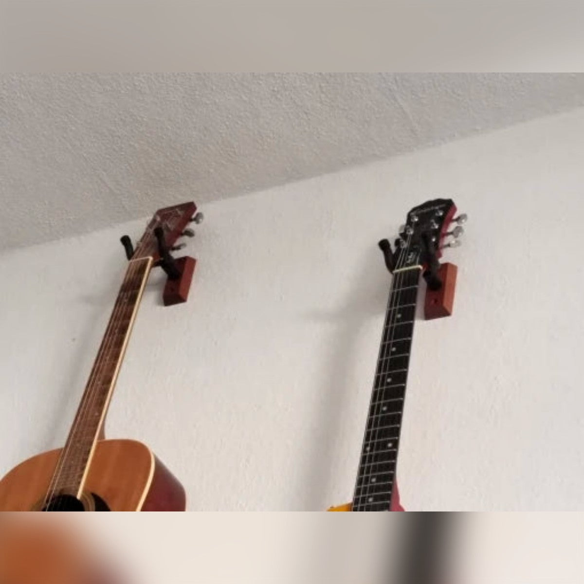 Kjøpers bilde: to gitarer henger på veggen i hvert sitt gitaroppheng