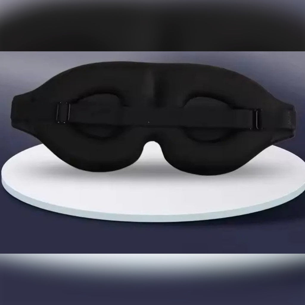 Svart 3D-sovemaske sett bakfra: fordypninger til øynene og stropp med spenne