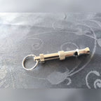 Kundens bilde: den sølvfargede hundefløyta med nøkkelring på en duk