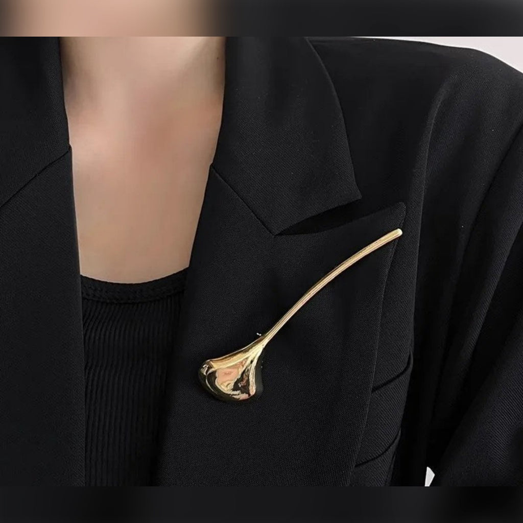 Gullfarget brosje på skrå på jakkeslaget til en blazer