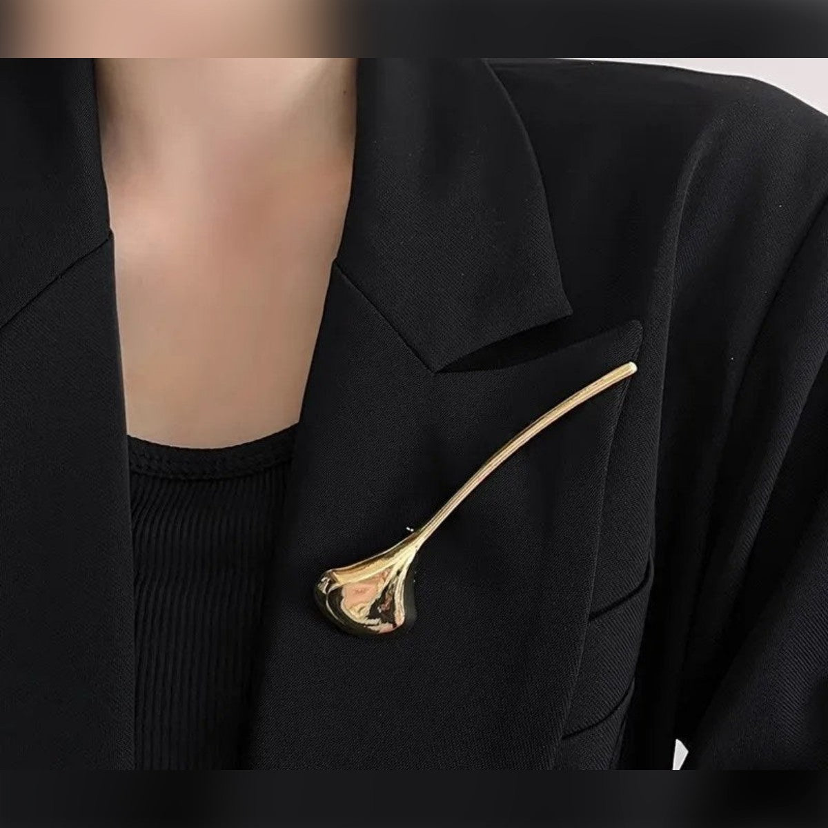 Gullfarget brosje på skrå på jakkeslaget til en blazer