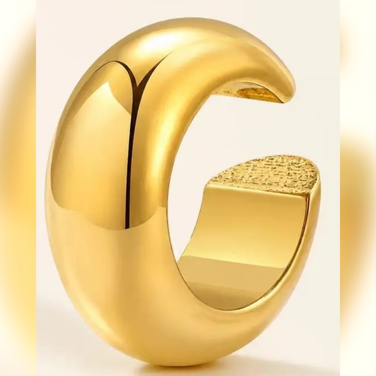 Gullfarget ear cuff på lys bakgrunn, C-form og hvelvet overflate