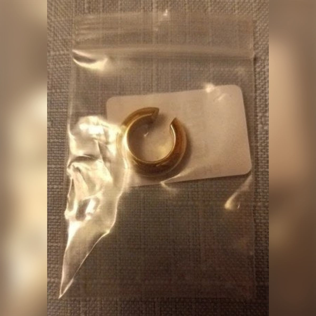 Kundens bilde: gullfarget ear cuff i en liten pose med glidelås