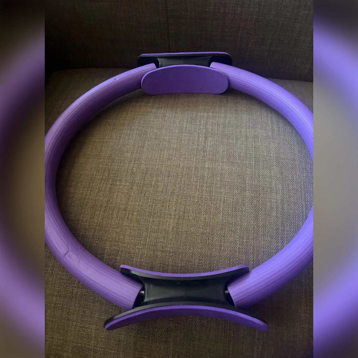 Kundens bilde: lilla pilates ring på en sofa, med ett håndtak øverst og ett nederst
