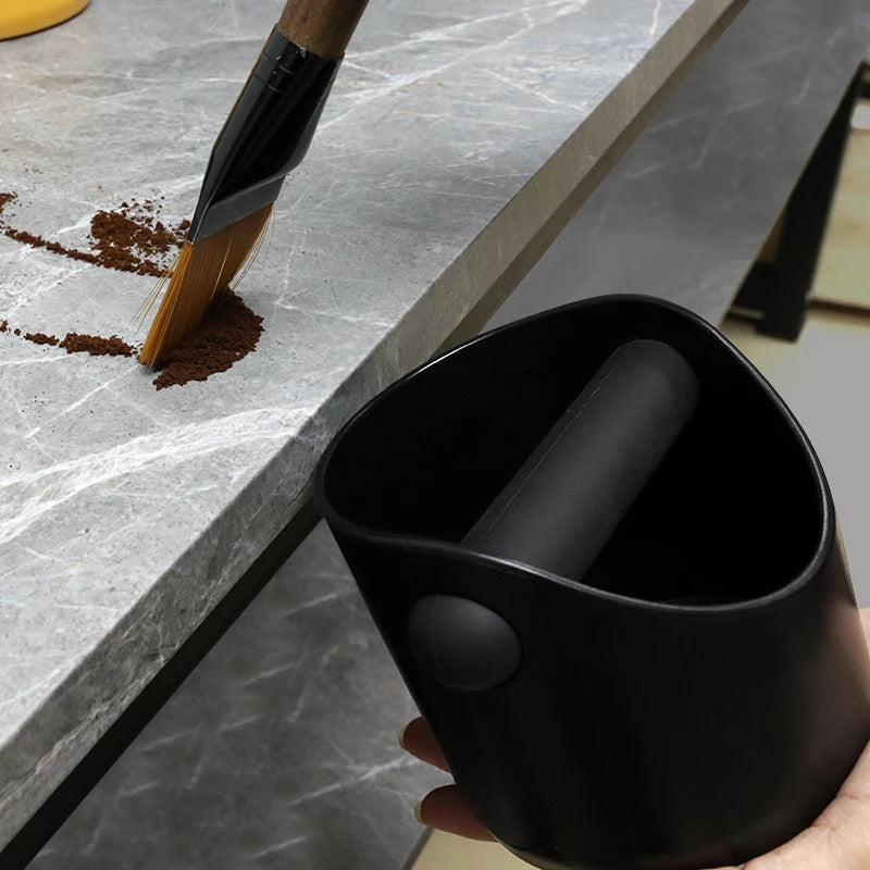 Knock boxen holdes inntil benkeplaten mens kaffegrut feies ned i den