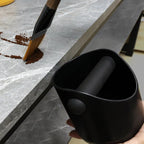 Knock boxen holdes inntil benkeplaten mens kaffegrut feies ned i den