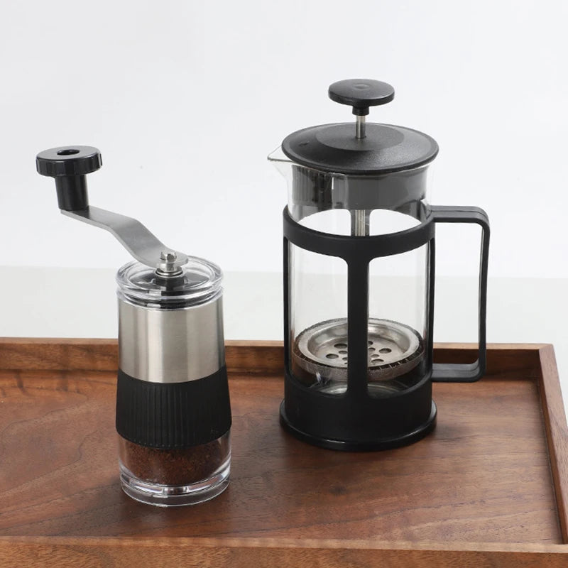 Kaffekvernen på et trebrett ved siden av en stempelkanne