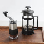 Kaffekvernen på et trebrett ved siden av en stempelkanne