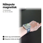 Svart magnetisk nålepute på et armbånd rundt håndleddet, ca. 24 cm utrullet