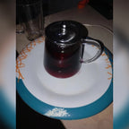 Kjøpers bilde: tekanne i glass fylt med hibiskuste på en tallerken
