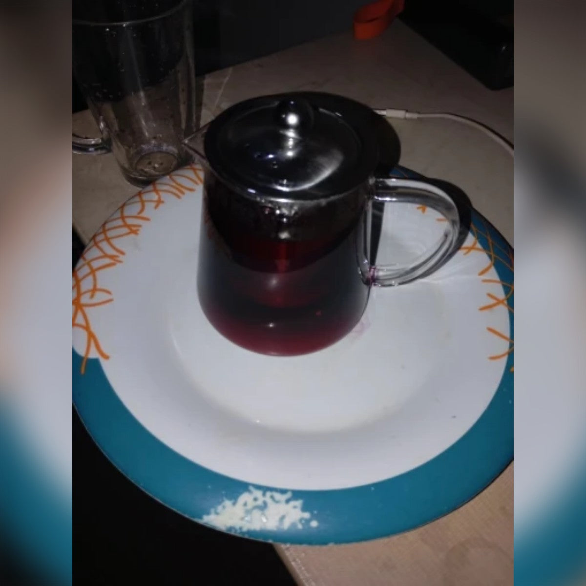 Kjøpers bilde: tekanne i glass fylt med hibiskuste på en tallerken