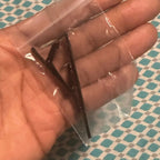 Kundens bilde: svart slipsnål i en plastpose i håndflaten